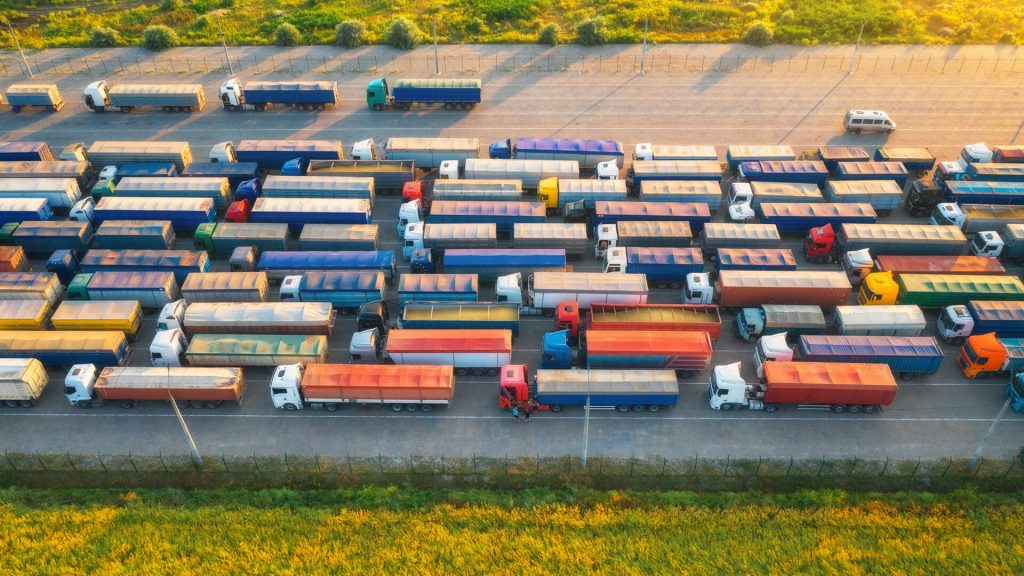 Vista dall'alto di numerosi rimorchi e camion parcheggiati in un'area di sosta, rappresentando la gestione rimorchi in logistica