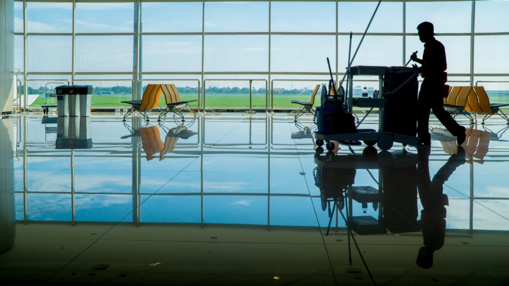 Operatore addetto alla pulizia in un terminal, contribuendo alla sicurezza personale aeroportuale in un ambiente ordinato e controllato